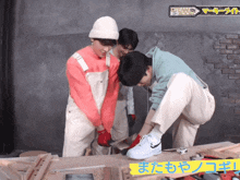 a group of young men are working on a piece of wood in a room with chinese writing on the wall behind them