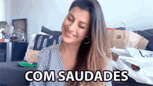 a woman sitting on a couch with the words com saudades written on the bottom