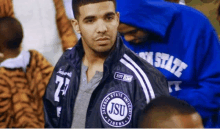 a man wearing a jackson state university jacket stands in a crowd