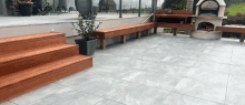 a patio with a wooden bench and steps and a pizza oven