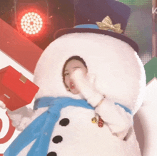 a woman in a snowman costume holds a red gift box