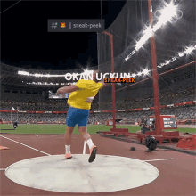 a man in a yellow shirt is throwing a discus in a stadium that says sneak-peek on it