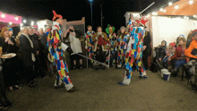 a group of people dressed in colorful costumes are standing in front of a sign that says ' a ' on it