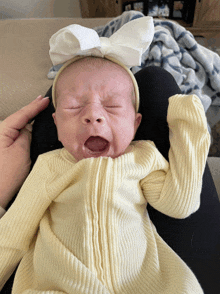 a newborn baby wearing a white headband is crying