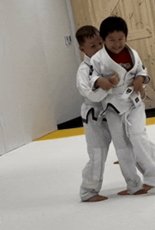 two young boys are practicing martial arts on a white mat