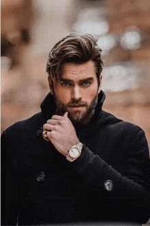 a man with a beard wearing a watch and a ring