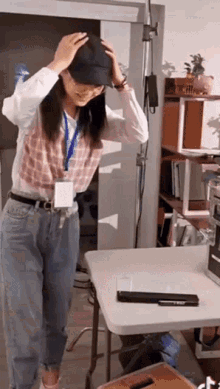 a woman wearing a name tag and a hat is standing in front of a table with a laptop on it