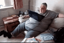 a man sits on a couch with a dell laptop