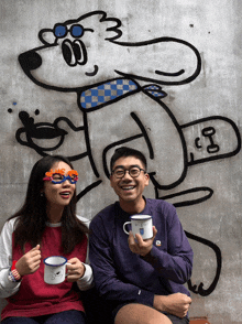 a man and a woman are sitting in front of a wall with a drawing of a dog with the number 3 on it