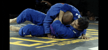 two men in blue kimonos are wrestling on a mat that says superfight