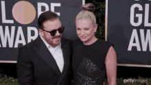 a man and a woman are posing for a picture on a red carpet in front of a sign that says globe awards