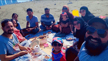 a group of people are having a picnic on the beach and one of them is wearing a spiderman hat