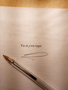 a pen is laying on a piece of paper that says vu et s ' en tape