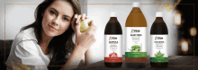 a woman holding an apple next to three bottles of vitae juice