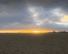 a sunset over a sandy beach with a few buildings in the distance