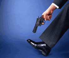 a man in a suit is holding a gun between his feet .