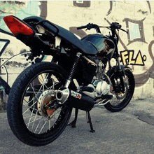 a black motorcycle is parked in front of a wall with graffiti on it that says fla