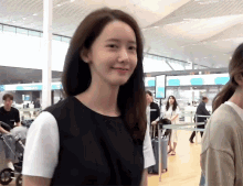 a woman in a black dress stands in front of a sign that says ' boarding gate ' on it