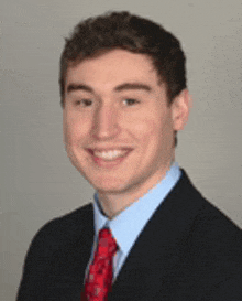 a young man wearing a suit and tie is smiling for the camera .