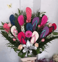 a vase filled with flowers and flip flops with a butterfly in the background