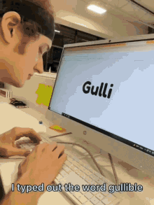 a man types out the word gullible on a computer screen