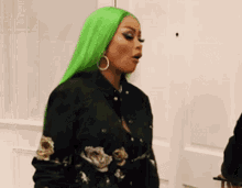 a woman with green hair and hoop earrings is standing in front of a white door .