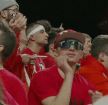 a man in a pittsburgh hat and sunglasses is sitting in a crowd of people