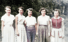 a group of women posing for a picture with one wearing a red shirt