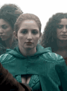 a woman in a green dress stands in a crowd of women