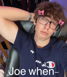 a man wearing glasses and a shirt that says joe when is sitting in a chair