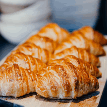 a bunch of croissants are lined up on a wooden cutting board