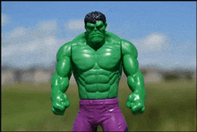 a green hulk toy with purple shorts and a blue sky in the background