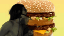 a man eating a very large hamburger with sesame seeds