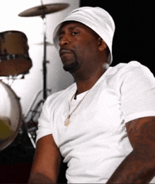 a man wearing a white hat is sitting in front of drums