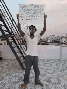 a man is holding up a white board with foreign writing