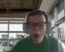 a man wearing headphones and glasses is looking at the camera with his mouth open .