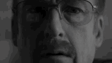 a close up of a man 's face with glasses on