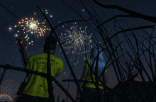 a man and a woman are watching fireworks and the man is wearing a yellow shirt that says dominion cargo