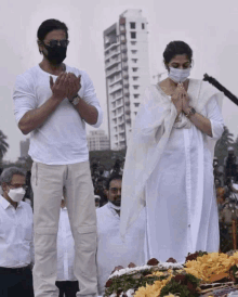 a man and a woman wearing face masks stand in front of a building