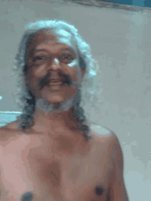 a shirtless man with long hair and a mustache is smiling