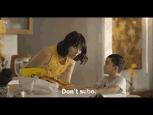 a woman is talking to a young boy at a table in a kitchen .