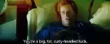 a man with red hair is laying on a couch and says you 're a big fat curly-headed fuck