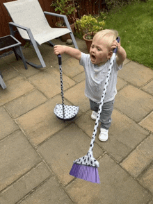 a little boy holding a purple broom and a polka dot mop