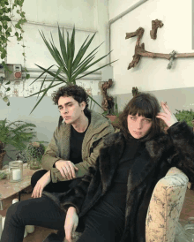 a man and a woman are sitting next to each other in front of plants