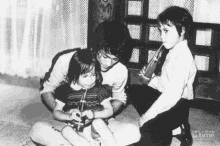 a black and white photo of a man and two children with time written on the bottom right corner