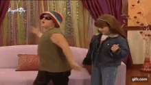 a boy and a girl are dancing in front of a couch .