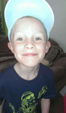 a young boy wearing a hat and a blue shirt with a skeleton on it