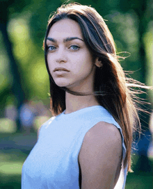 a woman in a white tank top is looking at the camera