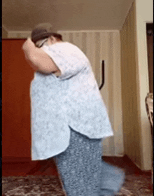 a woman in a white shirt and blue pants is dancing in a living room .