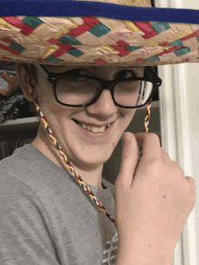 a young man wearing glasses and a sombrero smiles